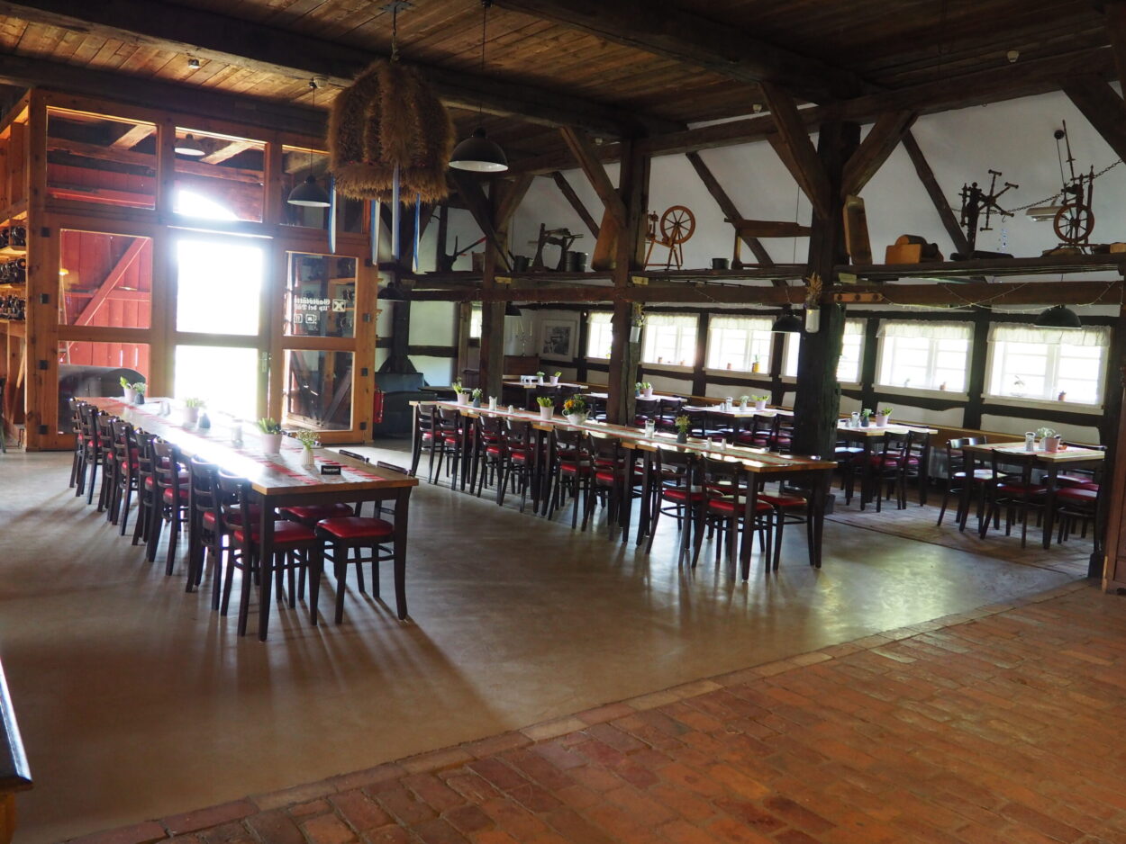 Innenraum der Gaststätte im Bauernhaus Strassen mit Tischen und Stühlen, Dekorationsobjekten und offenen Fachwerkhölzern.