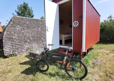 Außenansicht eines Bed&Bike-Wagens. Vor dem Wagen steht ein Fahrrad.