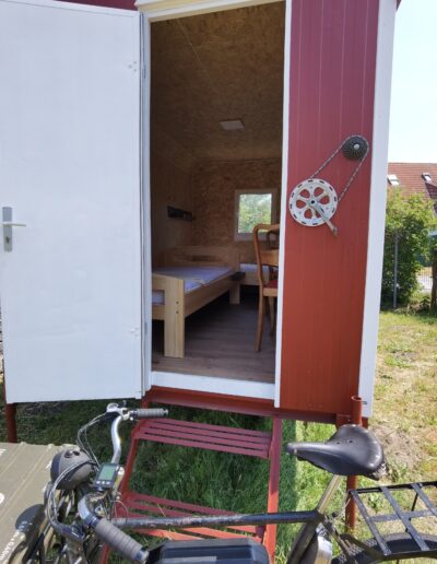 Außenansicht eines Bed&Bike-Wagens. Vor dem Wagen steht ein Fahrrad.