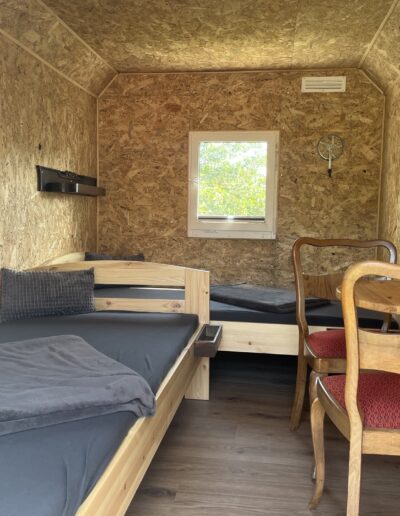 Innenansicht der Bed&Bike-Wagen mit zwei Betten, einem Wandtisch und zwei Stühlen.