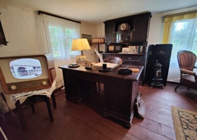 Die Stube von Heinrich Peters im Bauernhaus Klockenhagen mit Schreibtisch und einem alten Röhrenfernseher, auf dem ein Film über das Freilichtmuseum läuft.