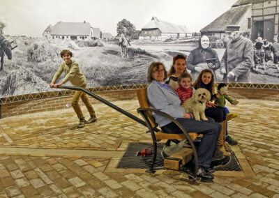 Eine Familie auf einem drehbaren Sitz in der Göpelscheune beim Betrachten des 360°-Panoramas, ein Kind dreht den Sitz.