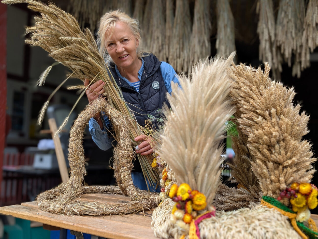 Eine Frau bindet mit Getreide eine Erntekrone.