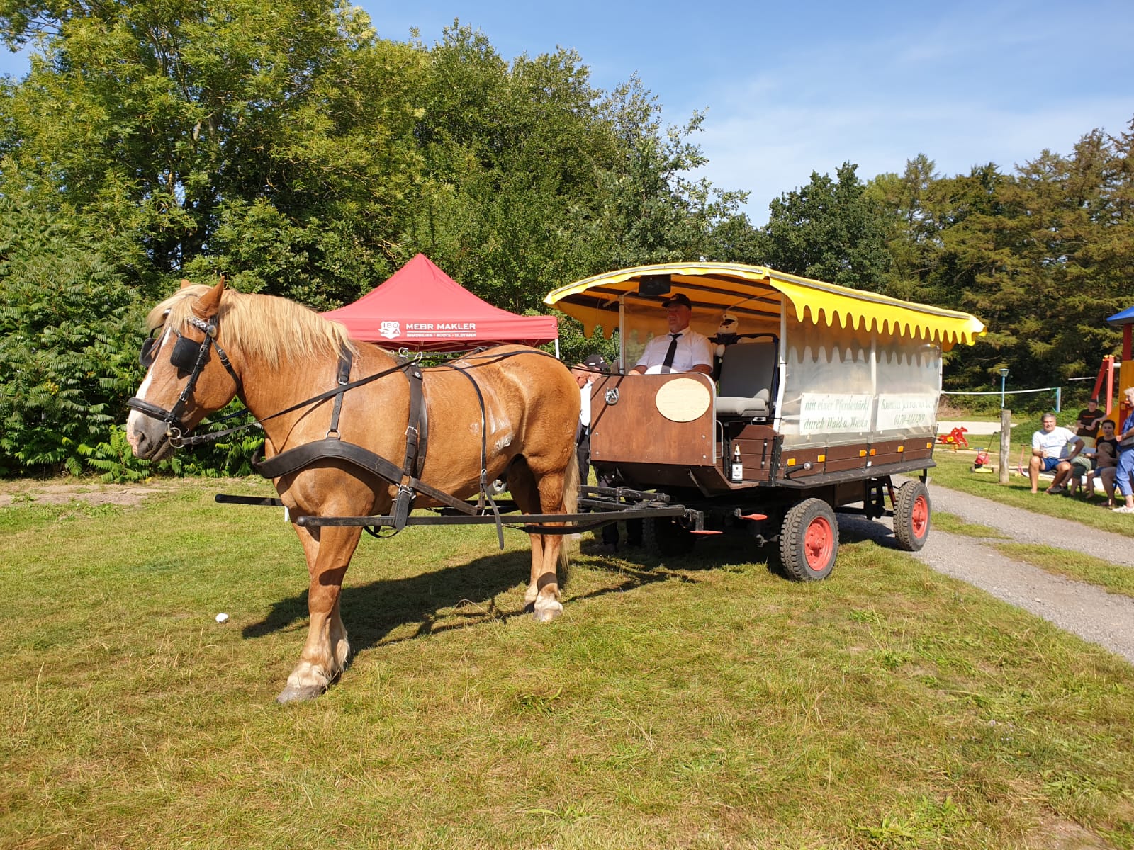 Ein Wagen, der Milchkannen transportiert. In den Milchkannen sind Sonnenblumen.